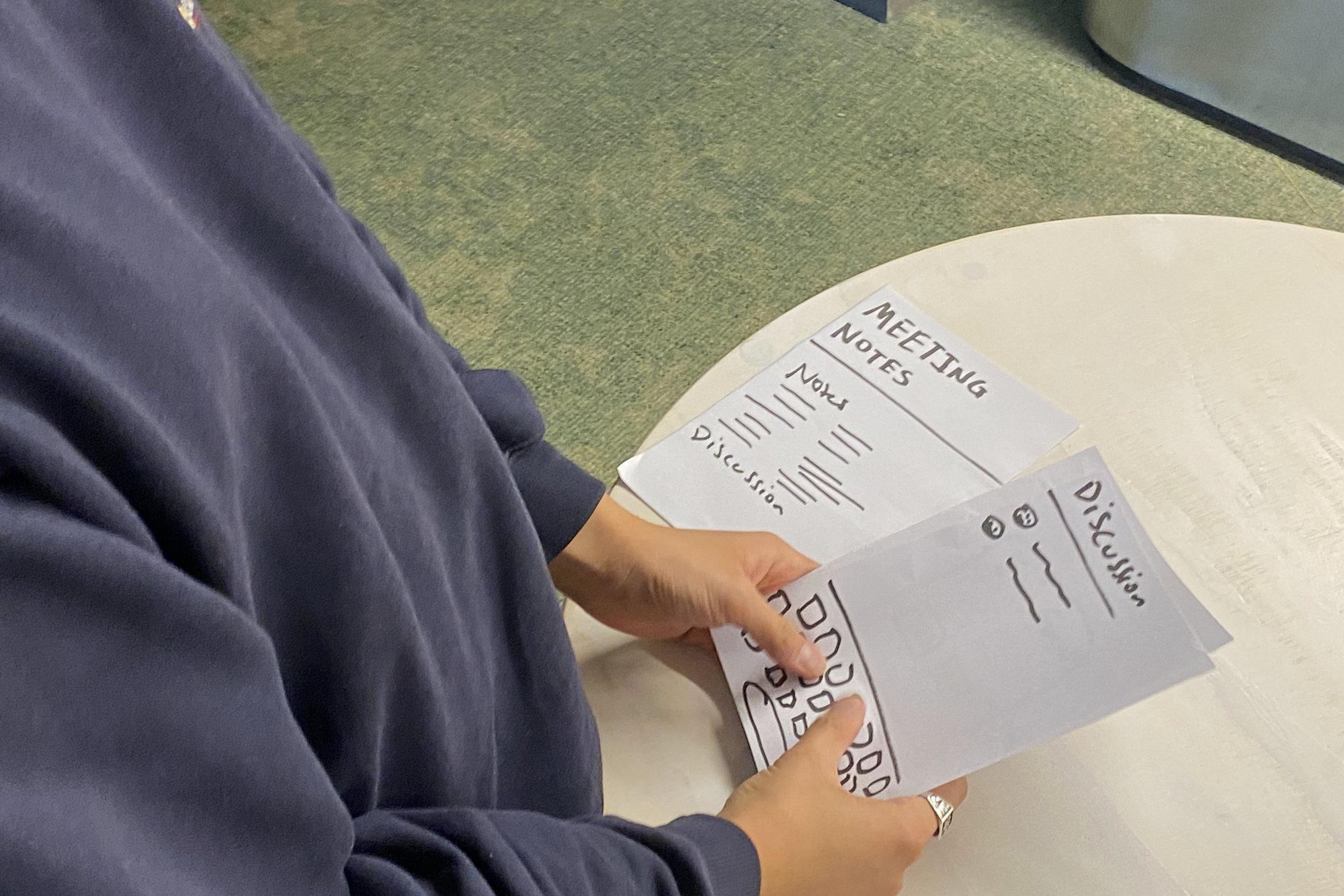 A participant holding paper screens for meeting notes and a discussion while testing prototype 2