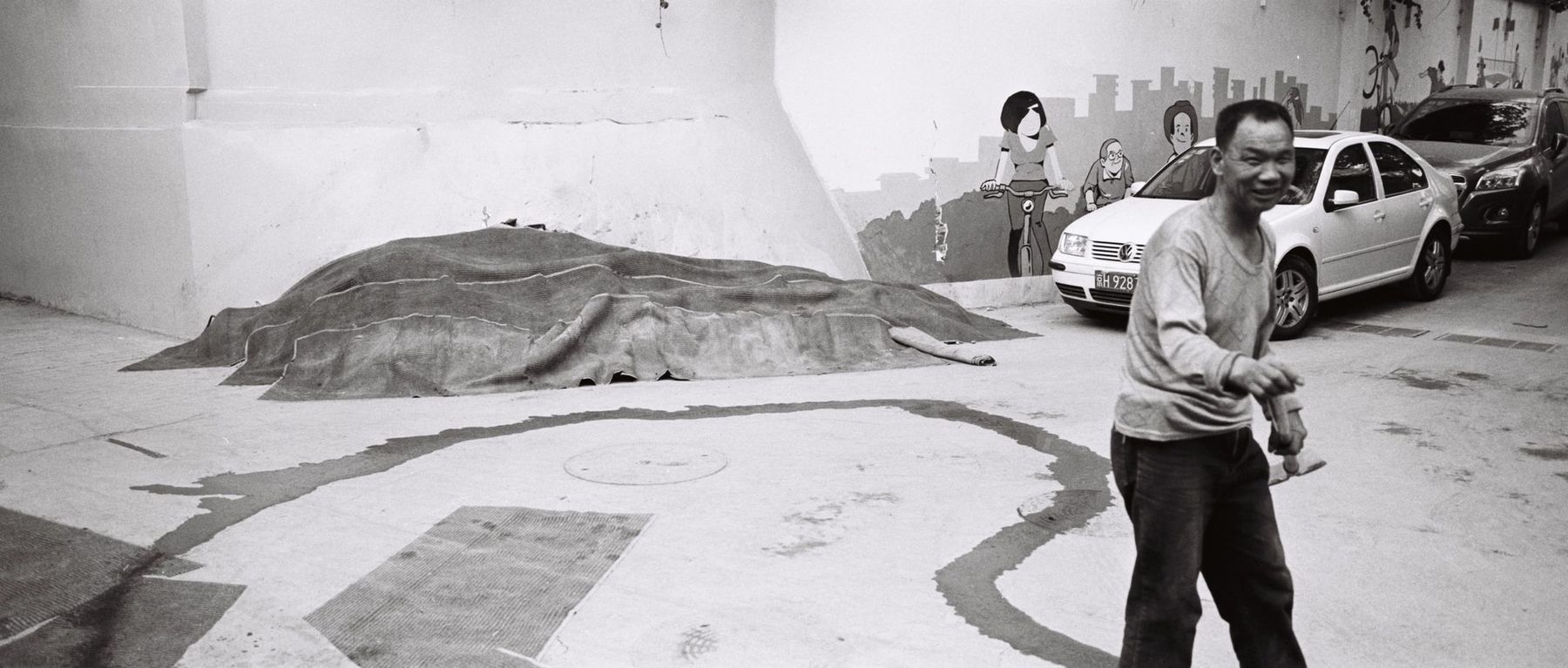 A man gesturing on a street beside a covered mound