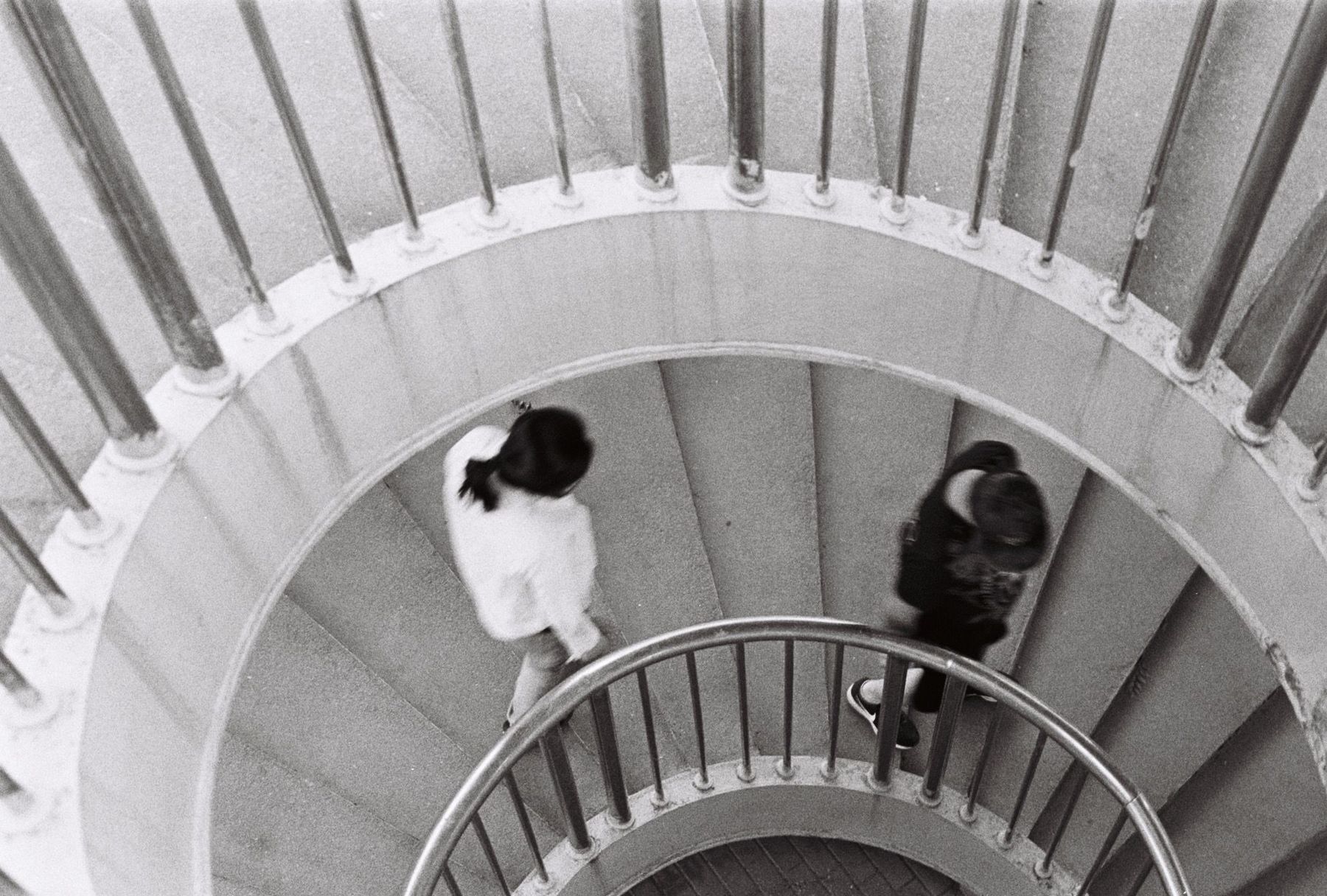 Looking down a spiral staircase at two people