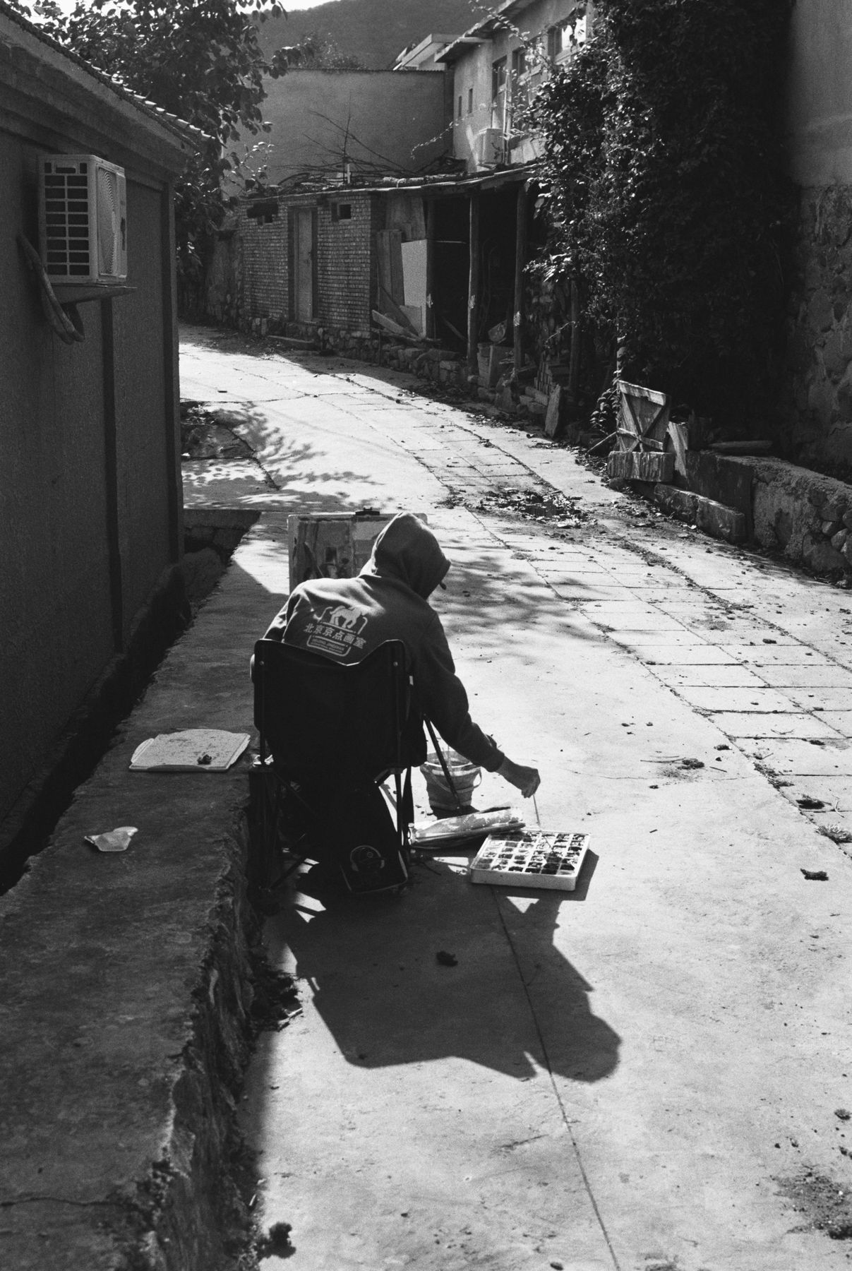 A person crouching in a sunlit alley